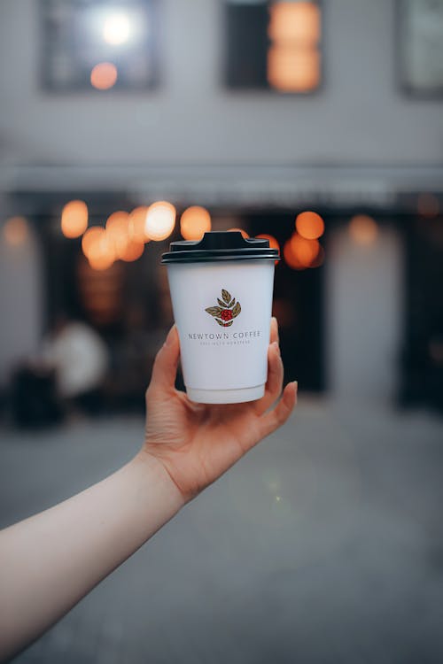 Person Holding a White Disposable Coffee Cup