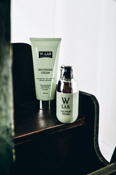 Stylish presentation of W-LAB whitening and sulphur creams on a wooden surface.