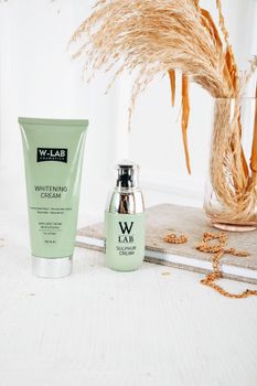 Stylish skincare product display with creams and dried grasses, emphasizing a natural aesthetic.
