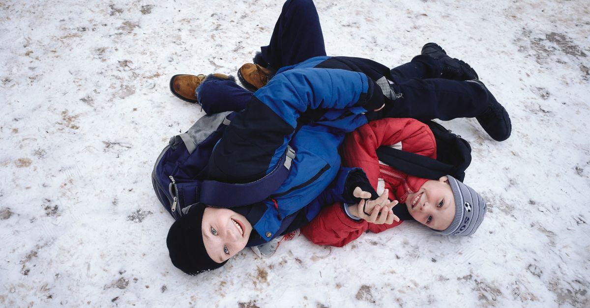 Finnish children playing outdoors in a snowy schoolyard, laughing