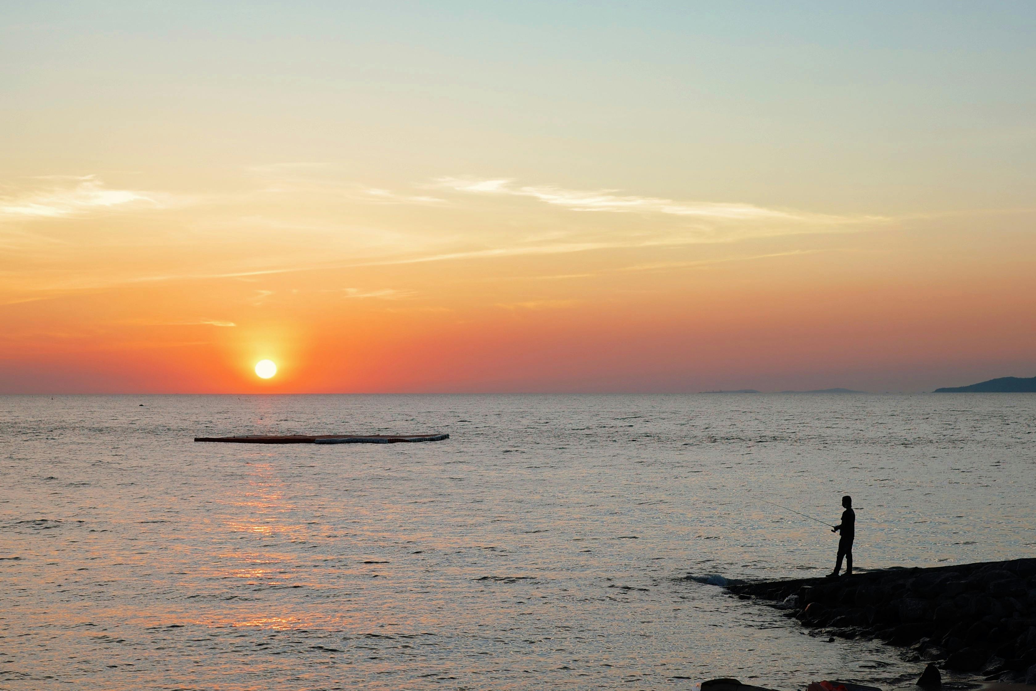 Man Kneeling on Rocks on Seashore · Free Stock Photo