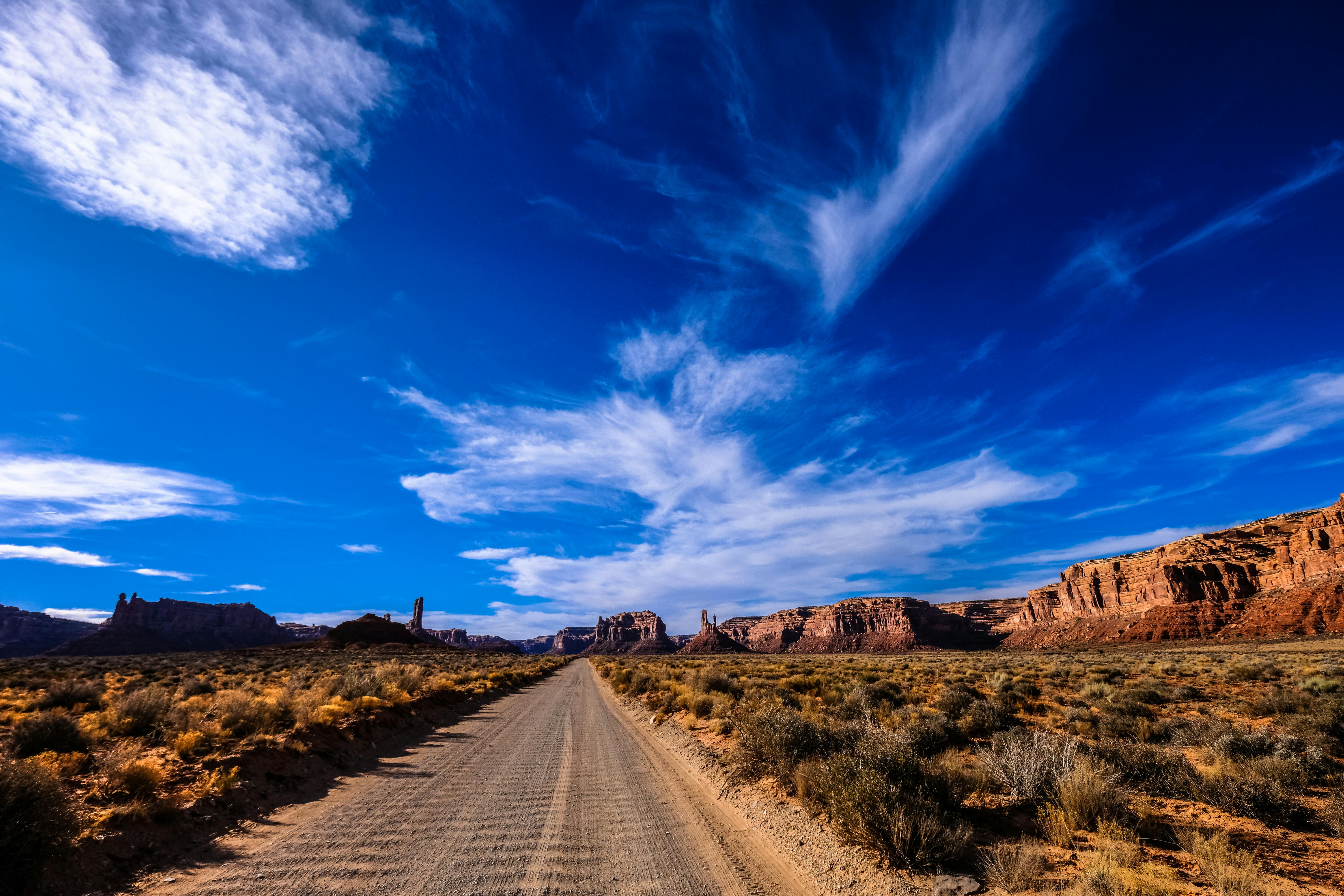 一条风景优美的沙漠公路，在广阔的蓝天下，云层密布，四周环绕着干旱的景观和岩石