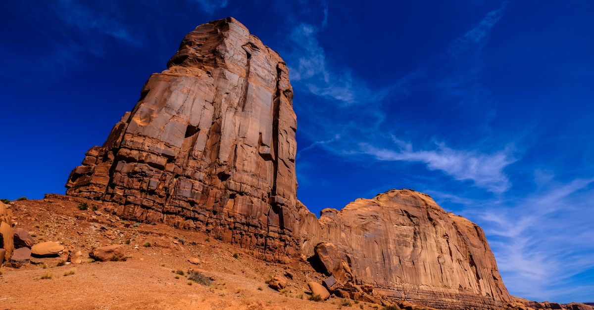 Majestic sandstone formations against a vibrant blue sky in a desert landscape.