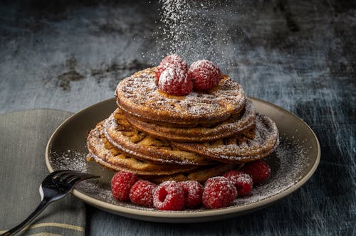 Free Tasty stack of pancakes with fresh raspberries and icing sugar dusting. Stock Photo