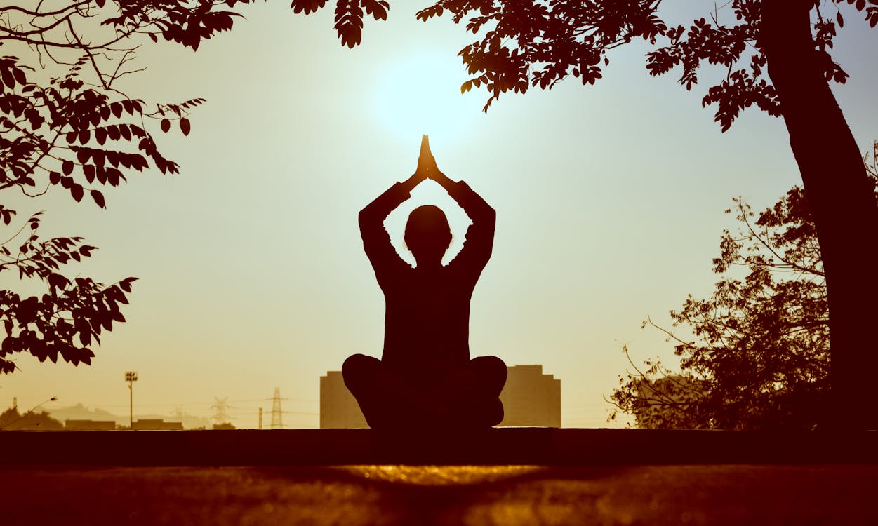 Person meditating as the sun rises.