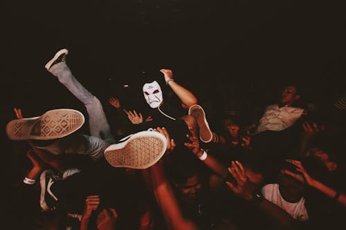 Crowd of People Carrying a Person Wearing a Mask