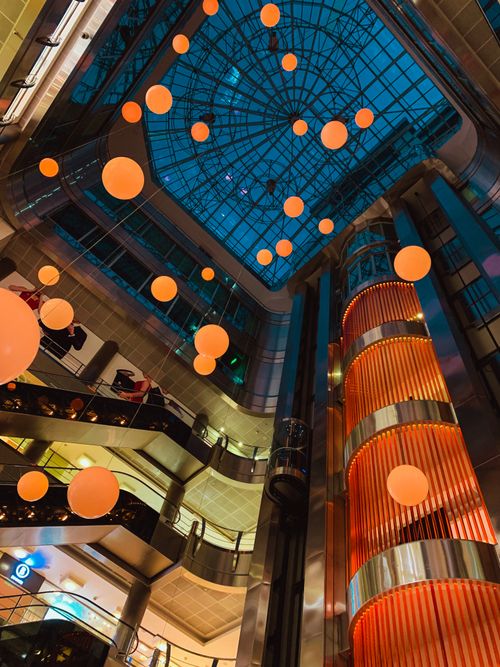 Free High-angle view of a shopping mall atrium decorated with orange globes and lights, capturing a festive ambiance. Stock Photo