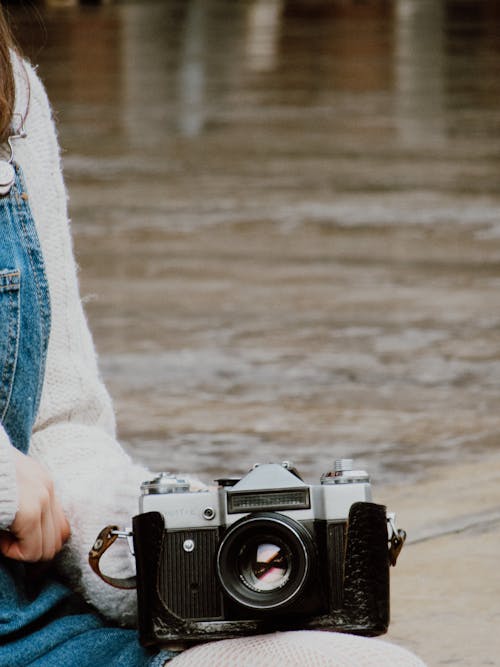 Person Holding a Vintage Black and Silver Camera
