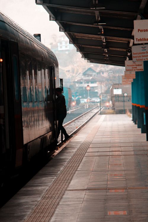 Free A silhouette of a person boarding a train on a quiet station platform. Stock Photo