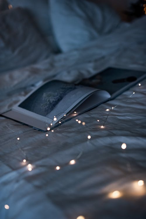String Lights on Bed Beside a Book