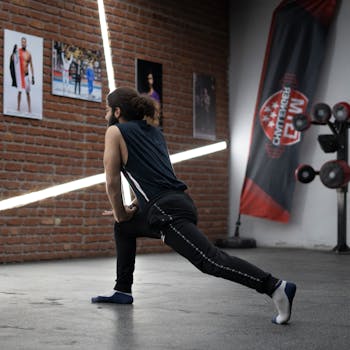 Adult man in activewear performing a warm-up stretch indoors in a modern gym.