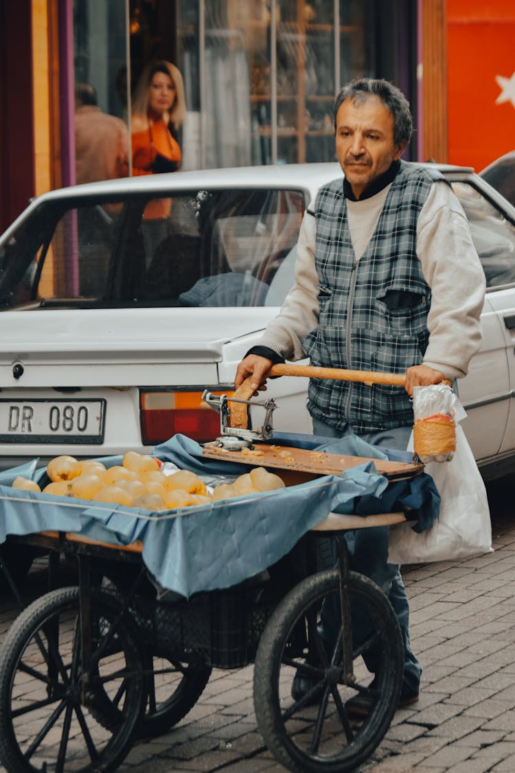 A Man Pushing A Cart On The Street