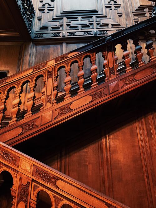 Free A beautifully crafted wooden staircase with ornate details, captured from below. Stock Photo