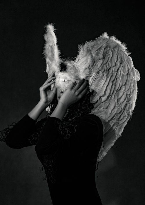 Free A black and white image of a woman wearing feathered wings and a unique headpiece, creating a mystical aura. Stock Photo