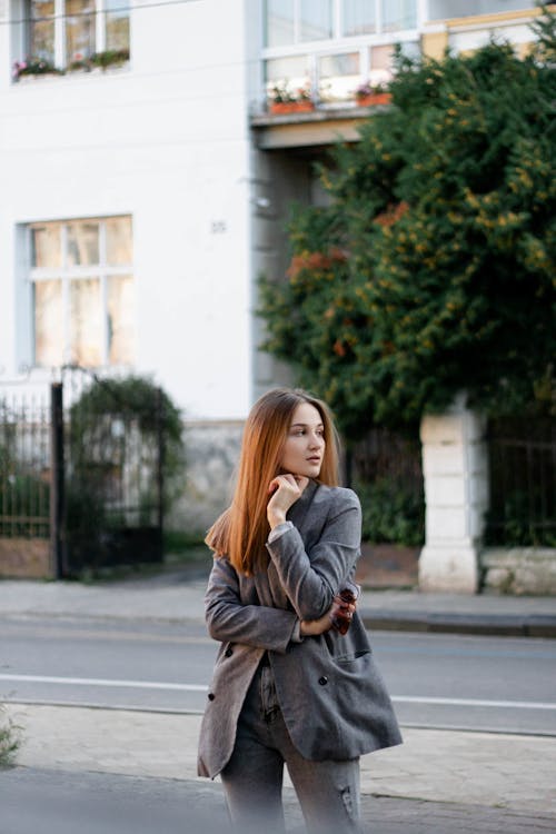 A Woman in Gray Coat Standing on the Street while Looking Over Shoulder