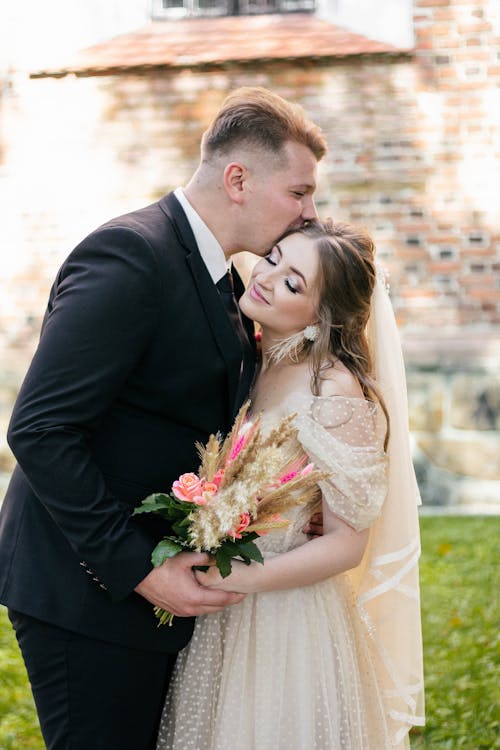 A Groom Kissing the Bride on the Head