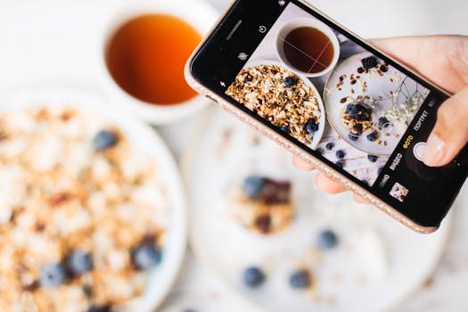 A vibrant image of a wholesome breakfast featuring granola, blueberries, and tea, shot using a smartphone.
