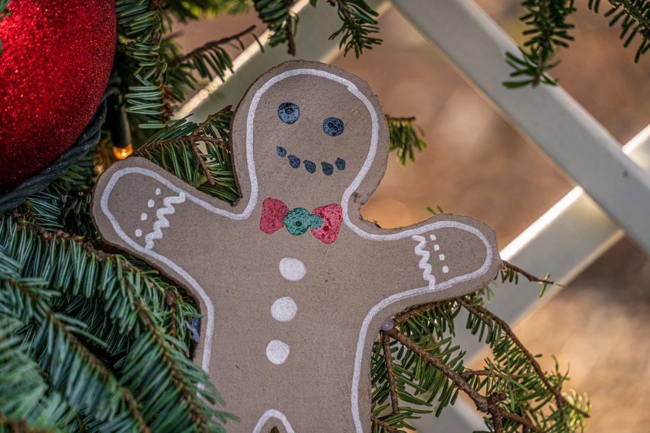 Close-up of a gingerbread ornament on a decorated Christmas tree branch.