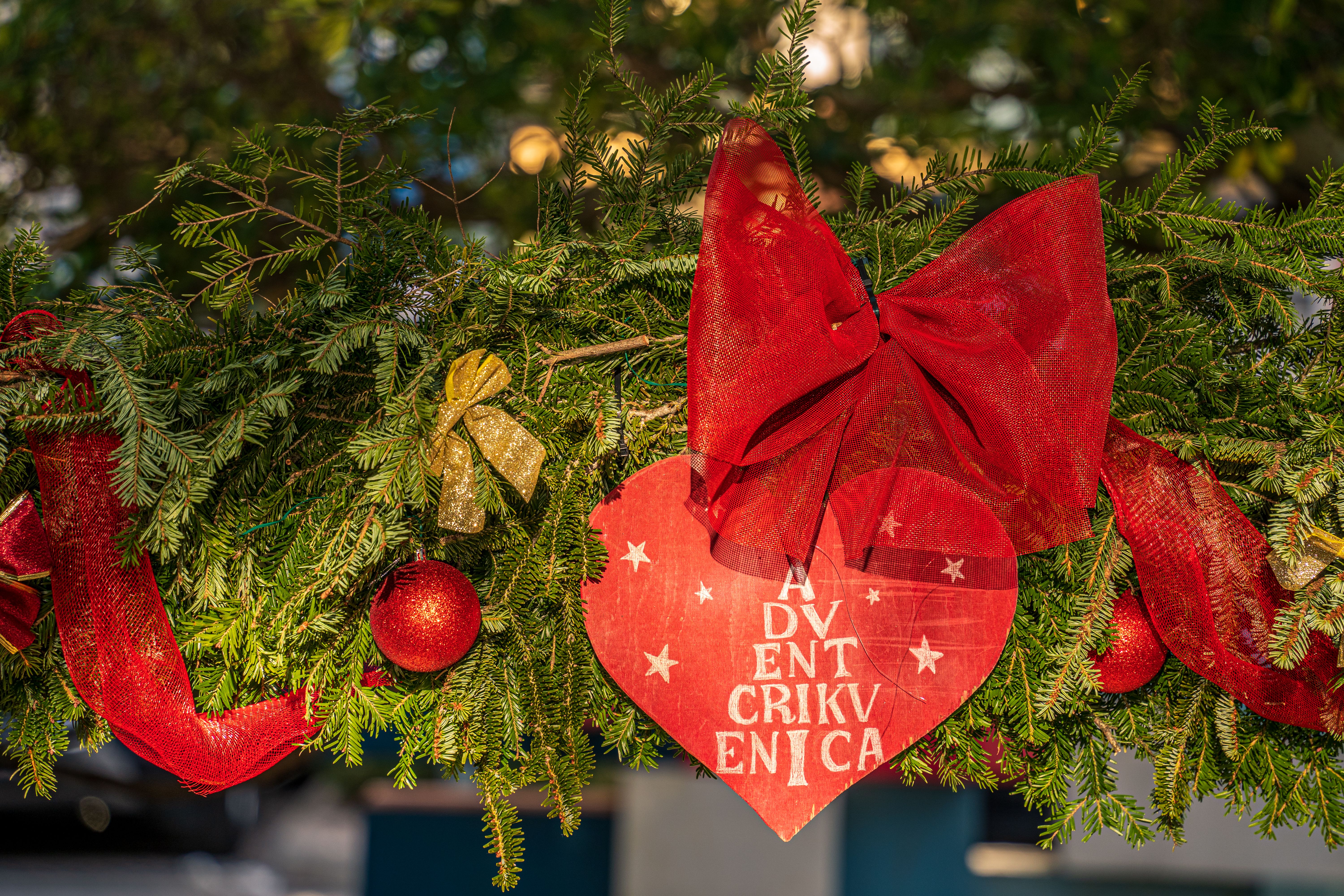 A vibrant Christmas wreath adorned with red bows and ornaments, perfect for holiday decoration.