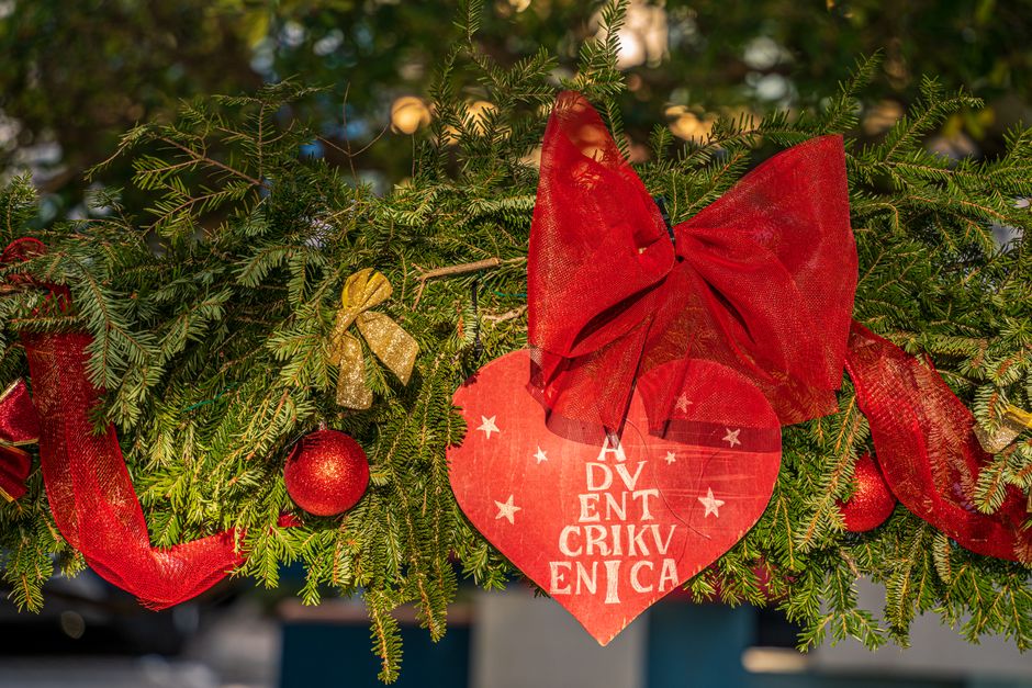 A vibrant Christmas wreath adorned with red bows and ornaments, perfect for holiday decoration.