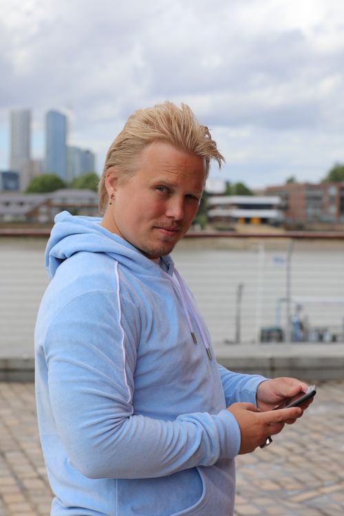 Free Caucasian man in blue hoodie using smartphone outdoors in London. Stock Photo