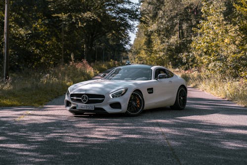 A White Mercedes Benz Parked on the Road Between Green Trees