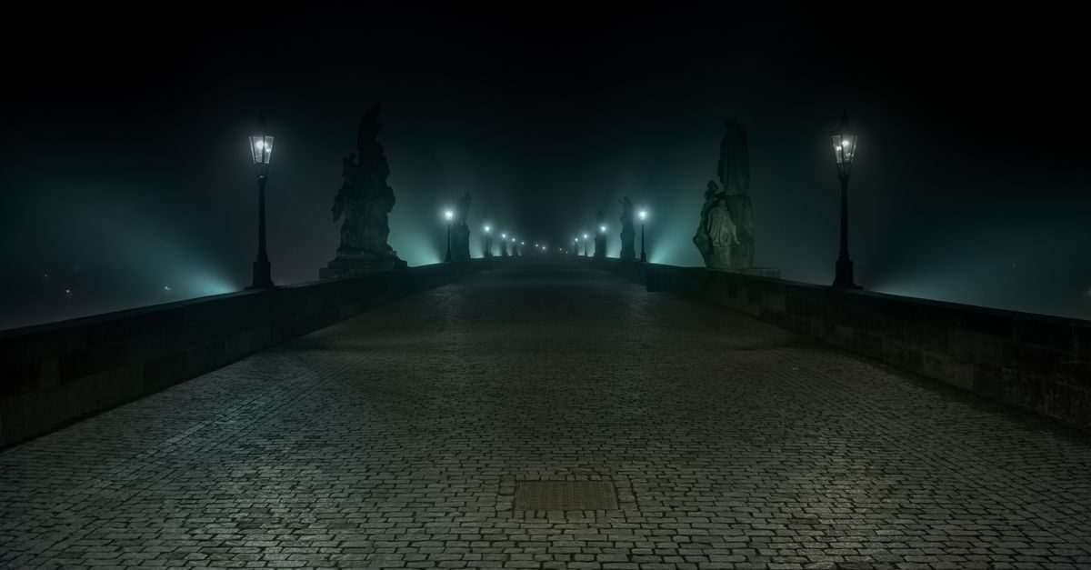 Mysterious night view of Charles Bridge, foggy and illuminated lamps, in Prague, Czechia.