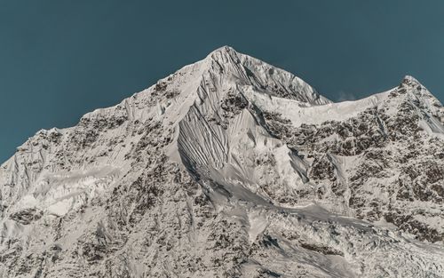 Free A breathtaking view of a snow-covered mountain peak under a clear blue sky in winter, located in the Diqing Tibetan Autonomous Prefecture, China. Stock Photo