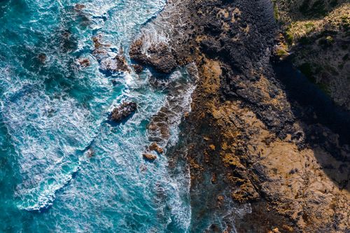 Free A breathtaking aerial view of ocean waves crashing against the rocky coastline in Victoria, Australia. Stock Photo