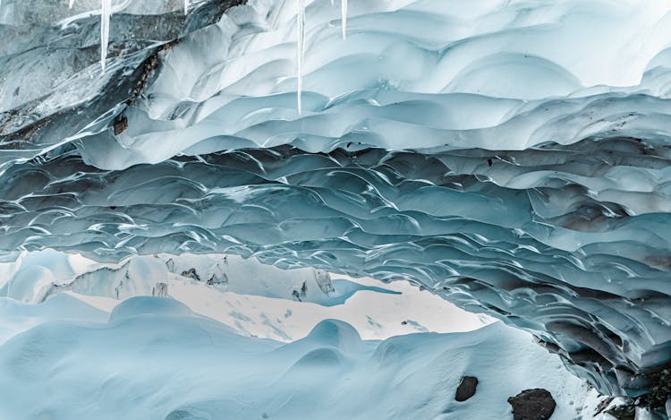 Icicles On Cave In Winter Landscape