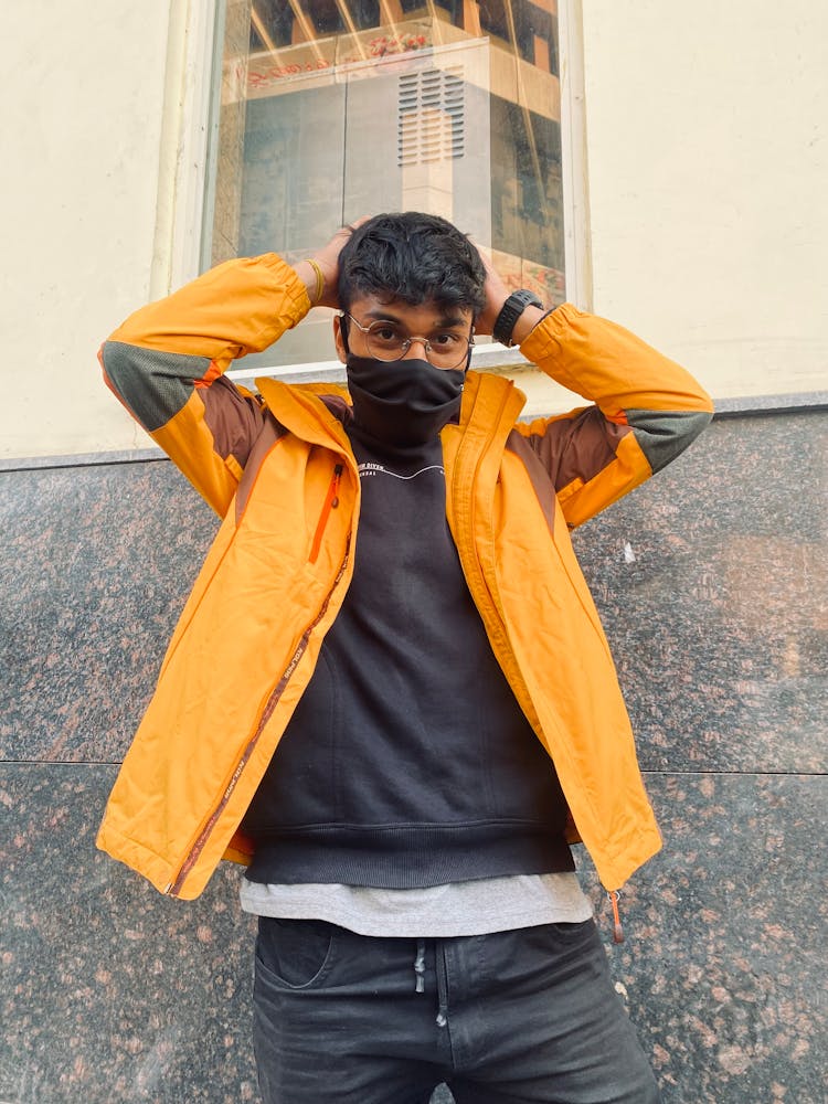 A Man In Yellow Jacket Wearing Black Face Mask