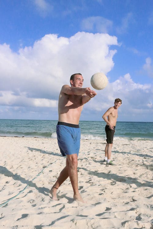 Free Shirtless Men Playing Volleyball on the Beach Sand Stock Photo