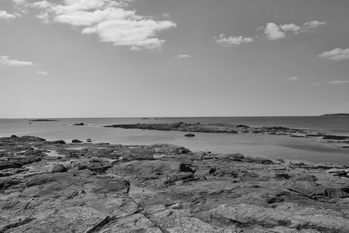 Free Peaceful rocky seashore landscape in black and white, capturing the vastness of the sea. Stock Photo