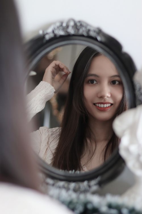 Free Beautiful Asian woman smiling at her reflection in a decorative mirror, Ho Chi Minh City. Stock Photo