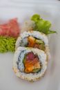 Delicious sushi roll with fresh salmon, avocado, and rice, served with garnishes for a tasty meal.