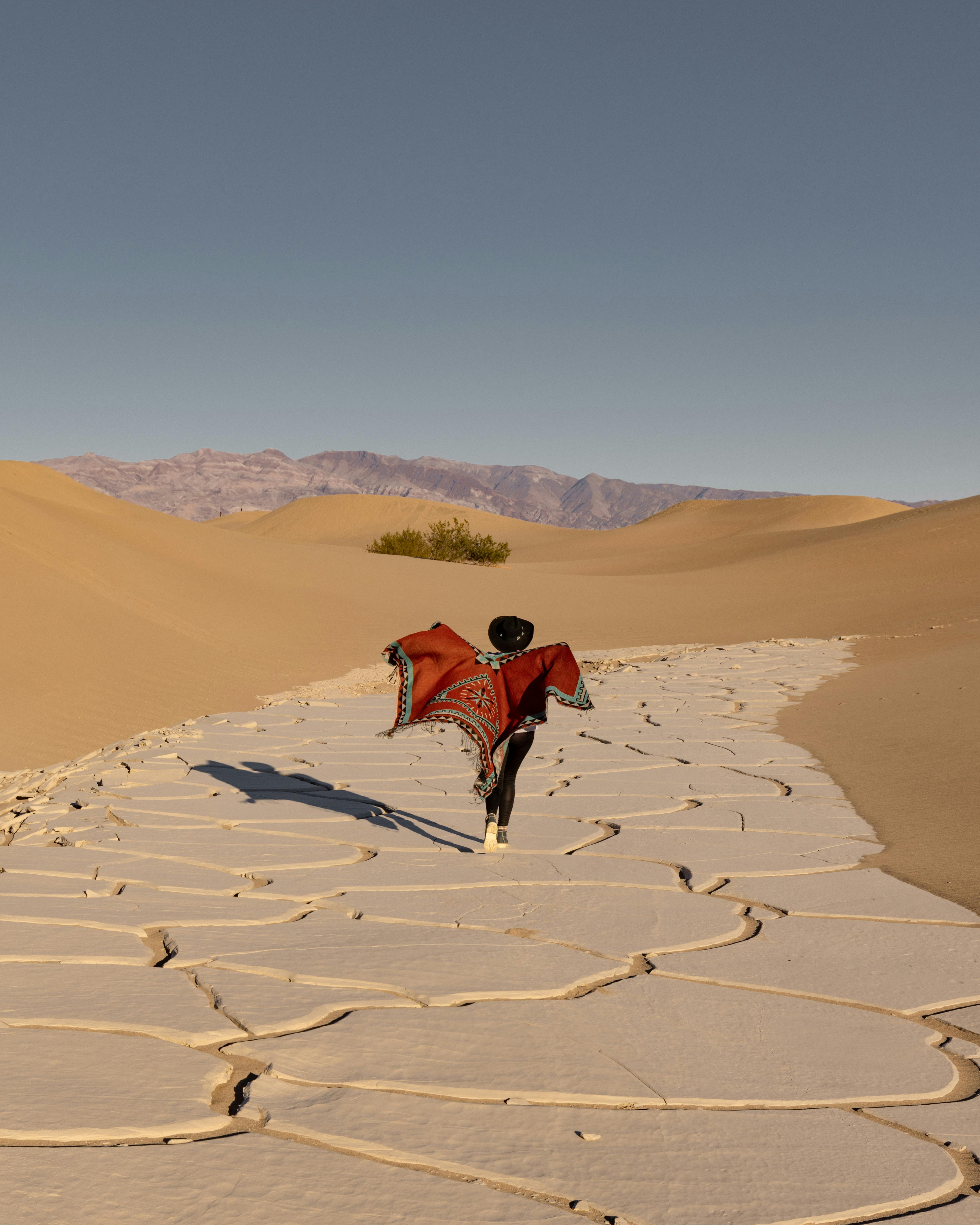 person walking in a poncho on the desert