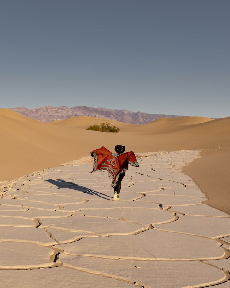 Person Walking In A Poncho On The Desert