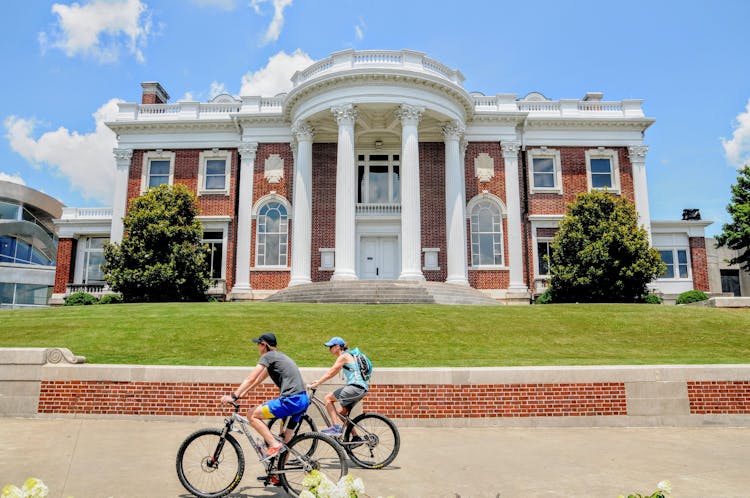 A Couple Riding Bicycles Passing The Faxon-Thomas Mansion In Chattanooga, Tennessee