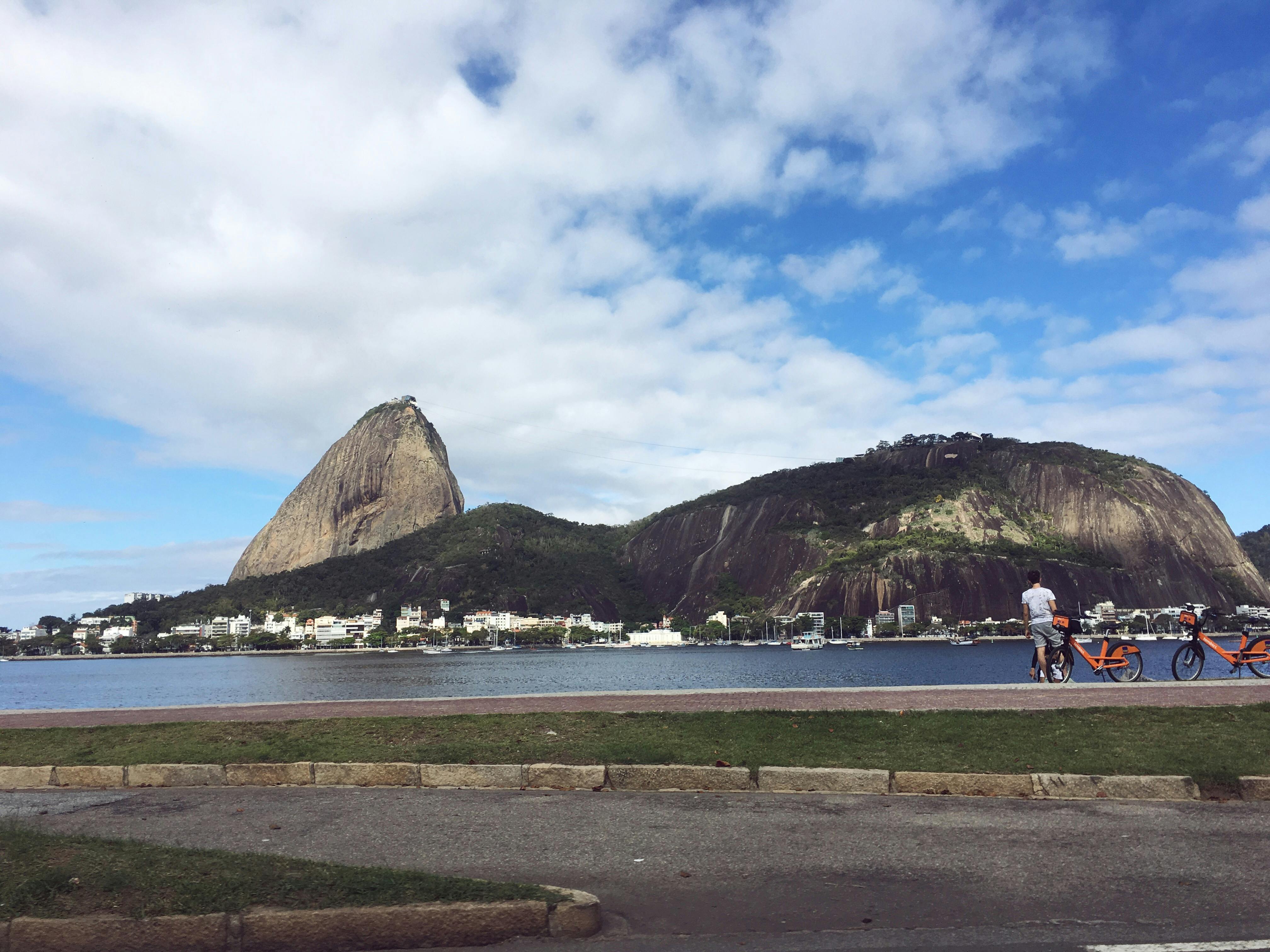 A picturesque view of Sugarloaf Mountain from Flamengo, Rio de Janeiro, with a bright blue sky and waterfront.