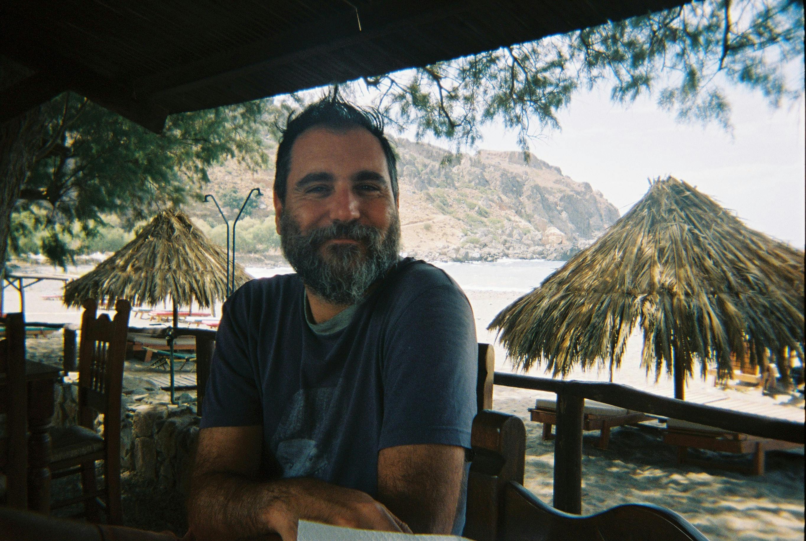 A man sits comfortably in a beachside restaurant, enjoying a serene view of the seashore.