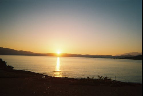  Body of Water Near Mountains During Sunset