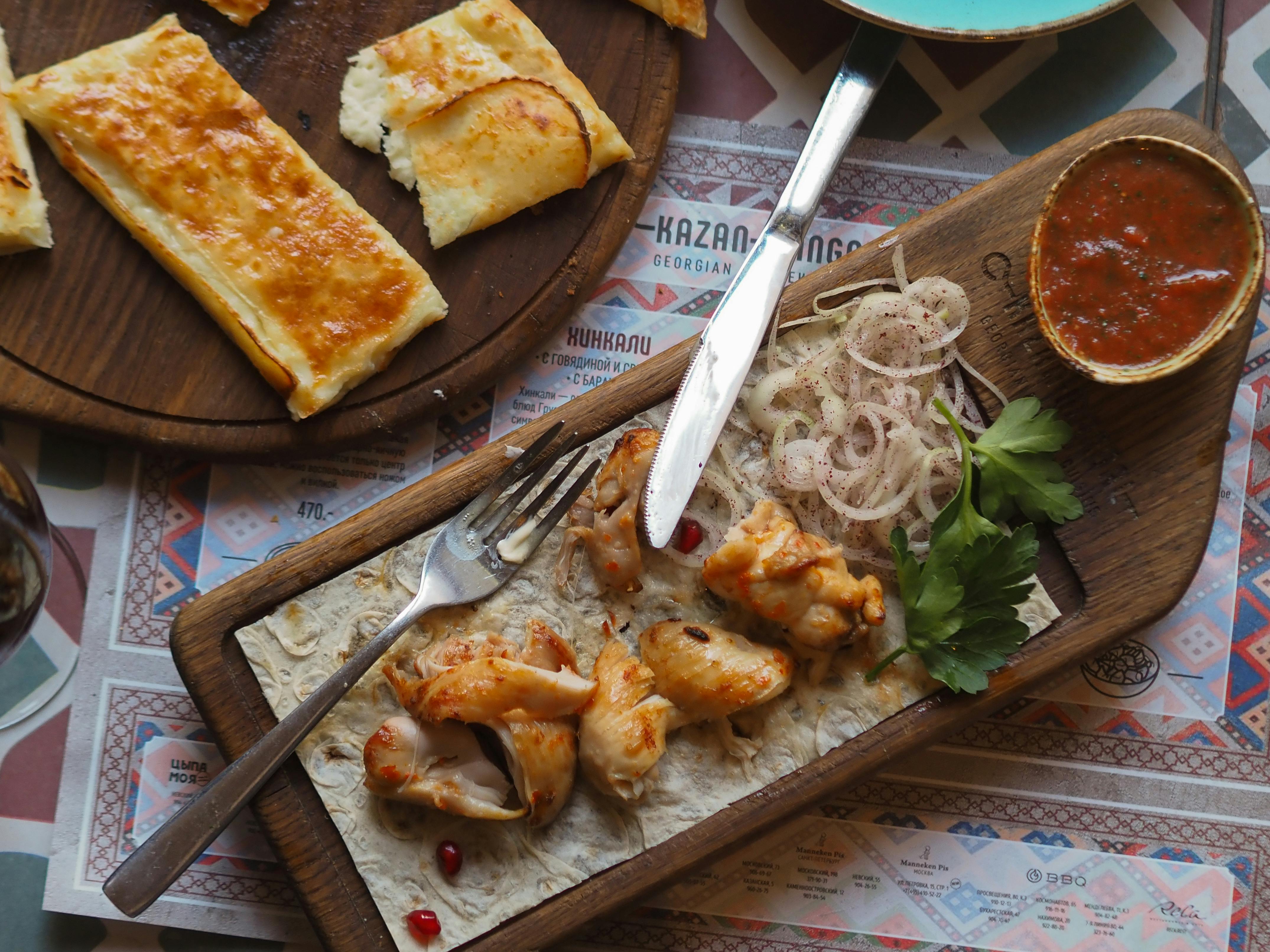 Tasty Georgian chicken served with flatbread and sauce on a wooden platter.
