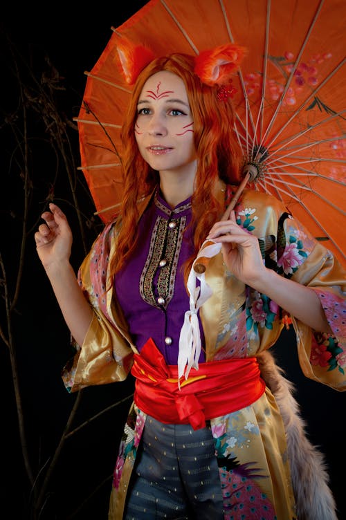 Woman in Colorful Costume Posing with an Umbrella