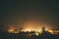 夜晚明亮的星空下，一座充满活力的城市被树木环绕