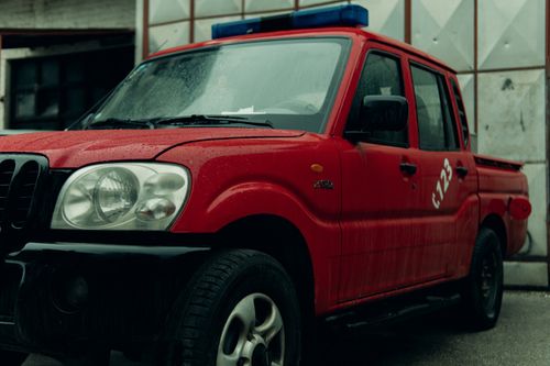 Free Close-up of a red pickup truck parked in a rainy environment with raindrops visible. Stock Photo