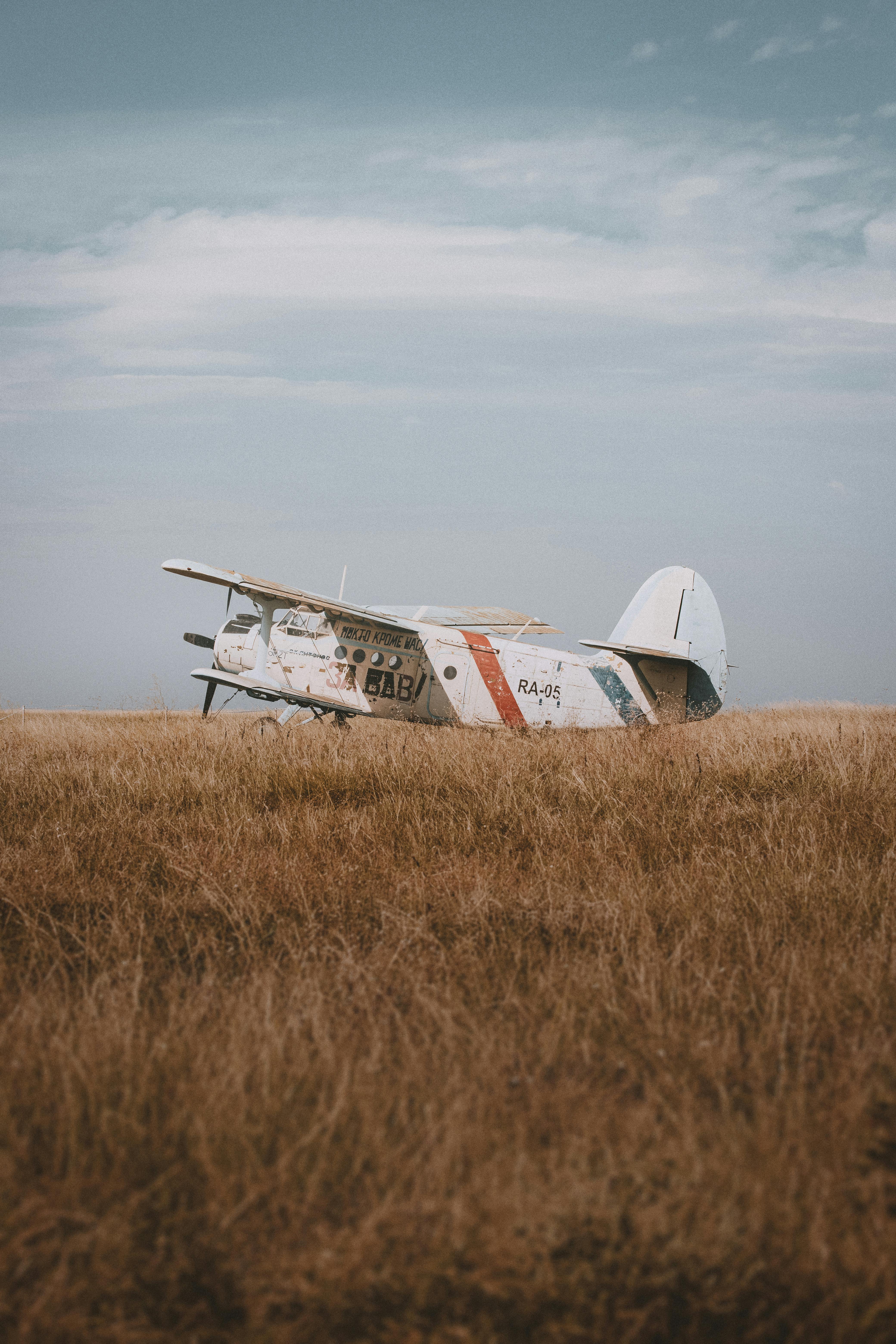 Old biplane standing quietly in a wide open field under a blue sky.