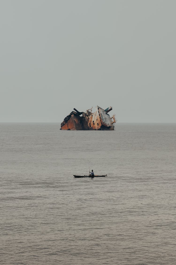 Man On Boat Against Wreck