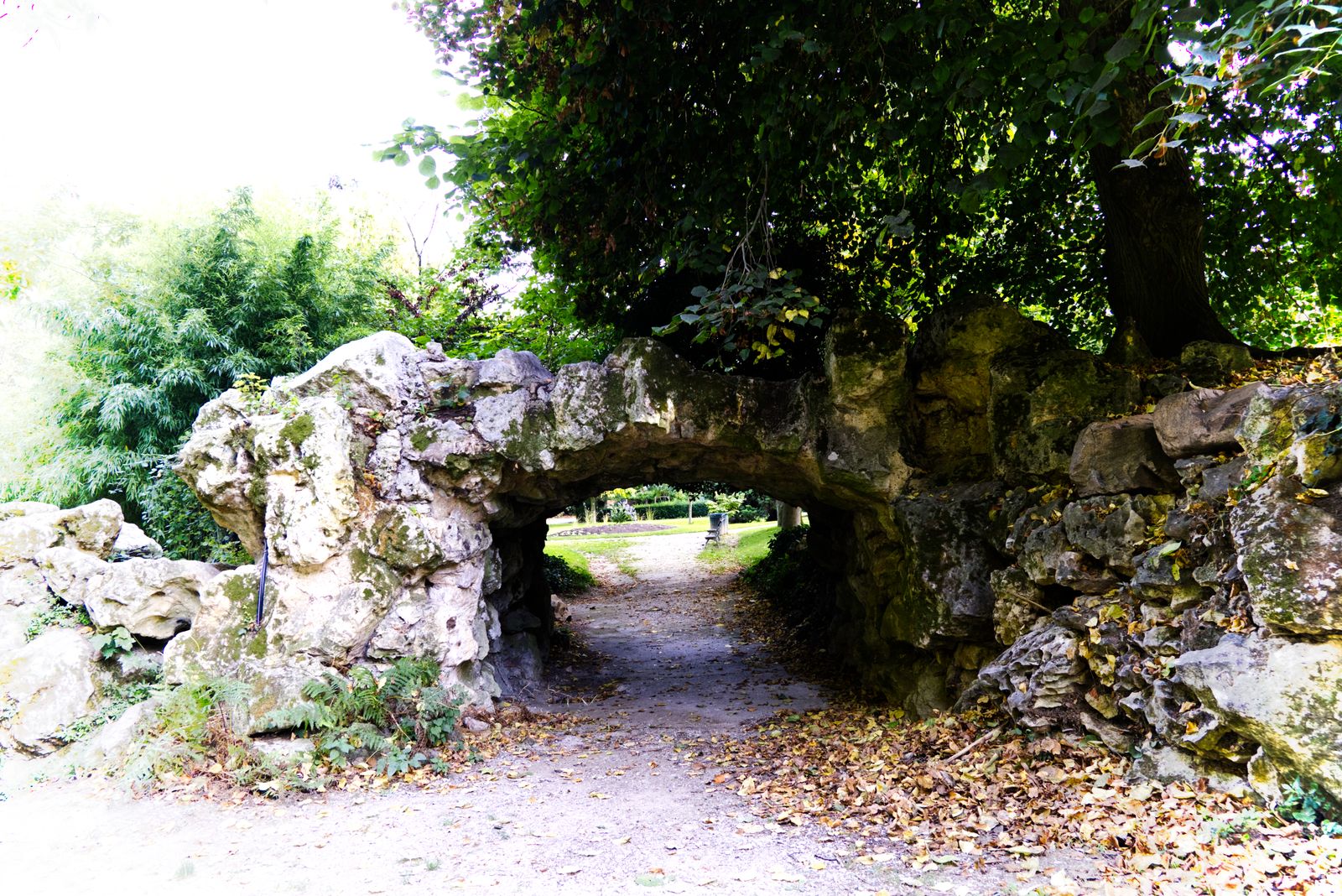 Arche de rocaille au-dessus d'une allée dans un jardin romantique