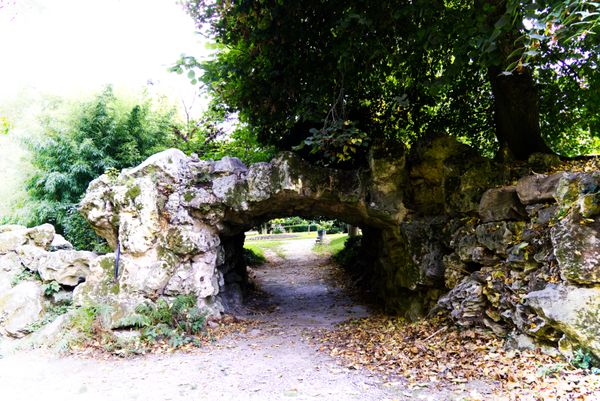 Arche de rocaille au-dessus d'une allée dans un jardin romantique