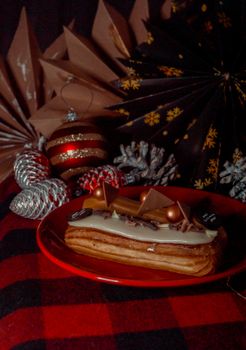 Delicious eclair dessert adorned with festive holiday decorations on a red plate.